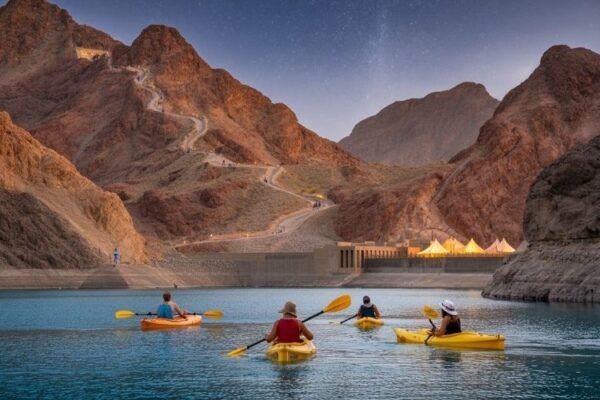 People kayaking on a serene blue lake surrounded by rocky mountains during a Hatta tour from Dubai.