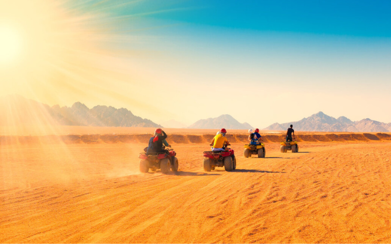 “Abu Dhabi sand dunes at golden sunset with desert safari jeeps and rolling sand hills.”