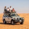 Group of people enjoying dune bashing on the red sand dunes in Dubai desert safari