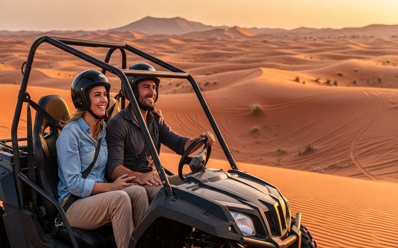 Couple-riding-a-2-seater-dune-buggy-on-Dubai-red-dunes-at-sunset-wearing-helmets-and-casual-adventure-clothes-enjoying-a-fun-desert-ride.