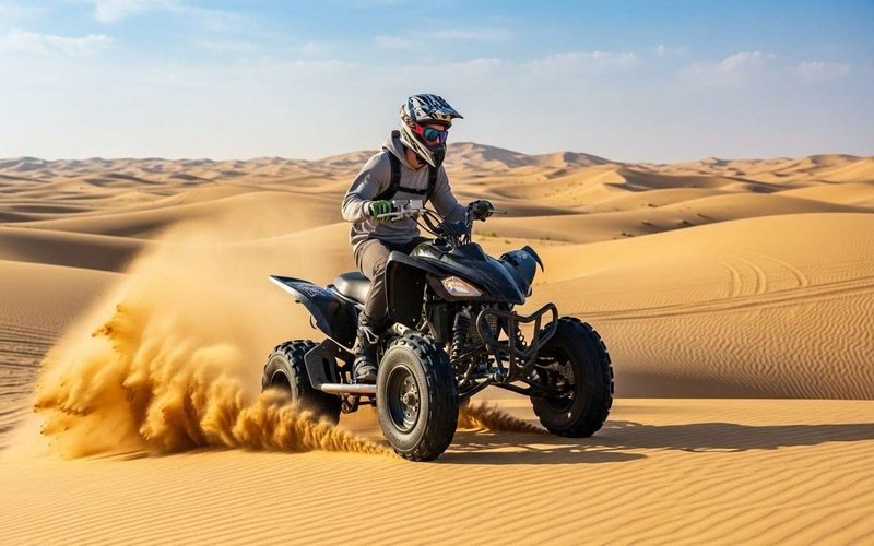 Person-riding-a-quad-bike-on-golden-sand-dunes-in-Dubai,-wearing-a-helmet-and-sunglasses,-kicking-up-sand.