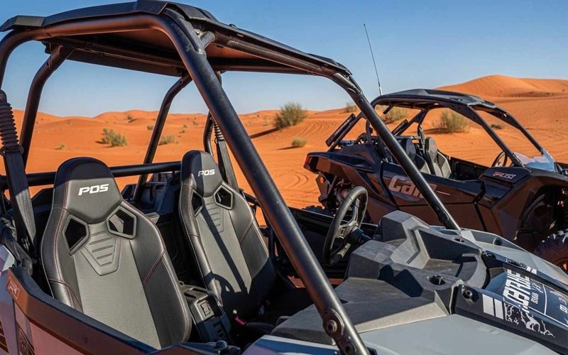 Polaris-RZR-and-Can-Am-Maverick-2-seater-dune-buggies-parked-on-red-Dubai-dunes-showing-seats-roll-cage-and-off-road-design.