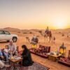 Peaceful desert safari in Dubai at sunset with seniors and a family enjoying a camel ride near a softly lit Bedouin camp with cultural activities.